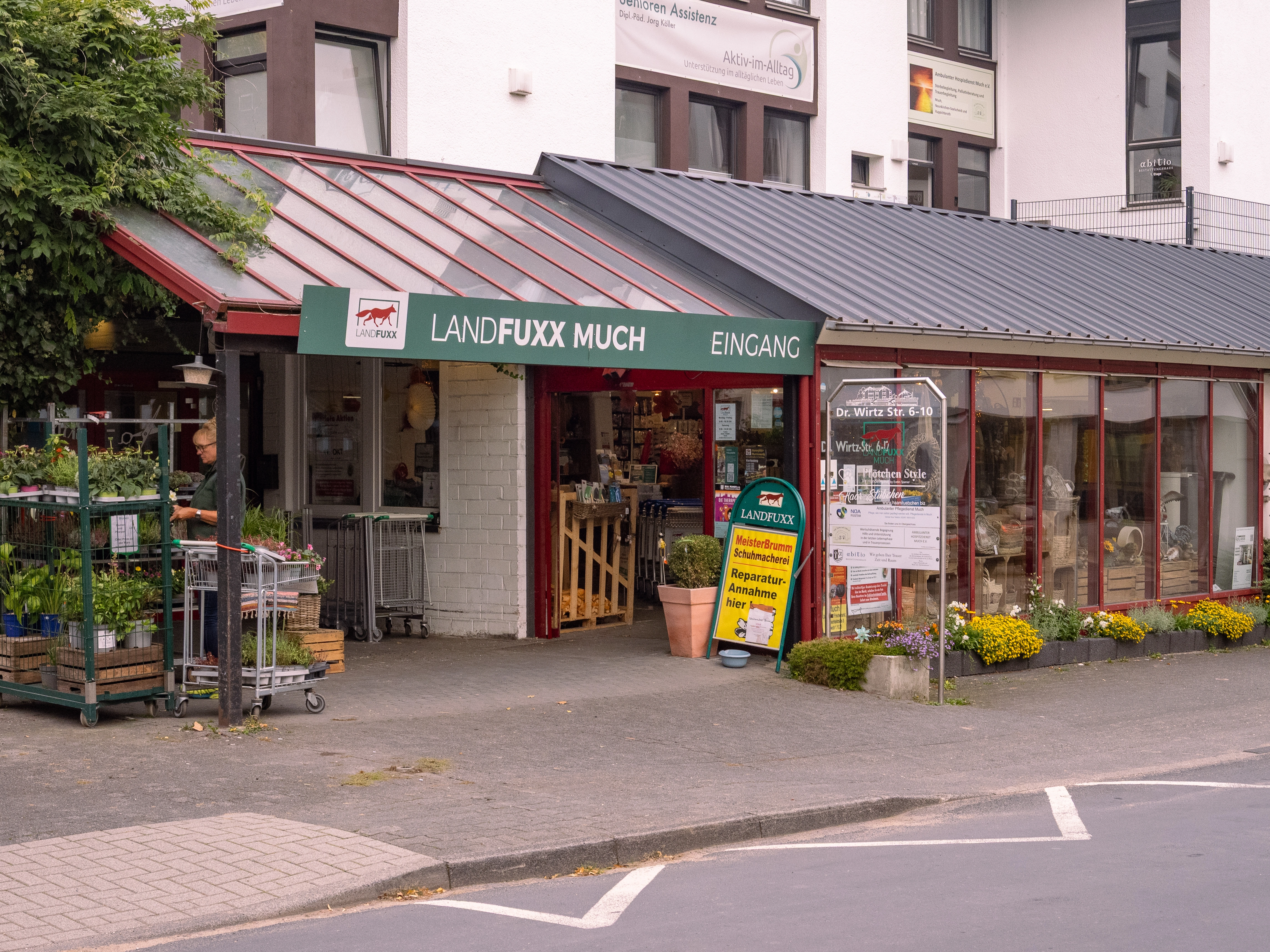 Der Außenbereich des Landfuxx Much mit Pflanzen, Blumen und verschiedenen Pflanzkübeln.