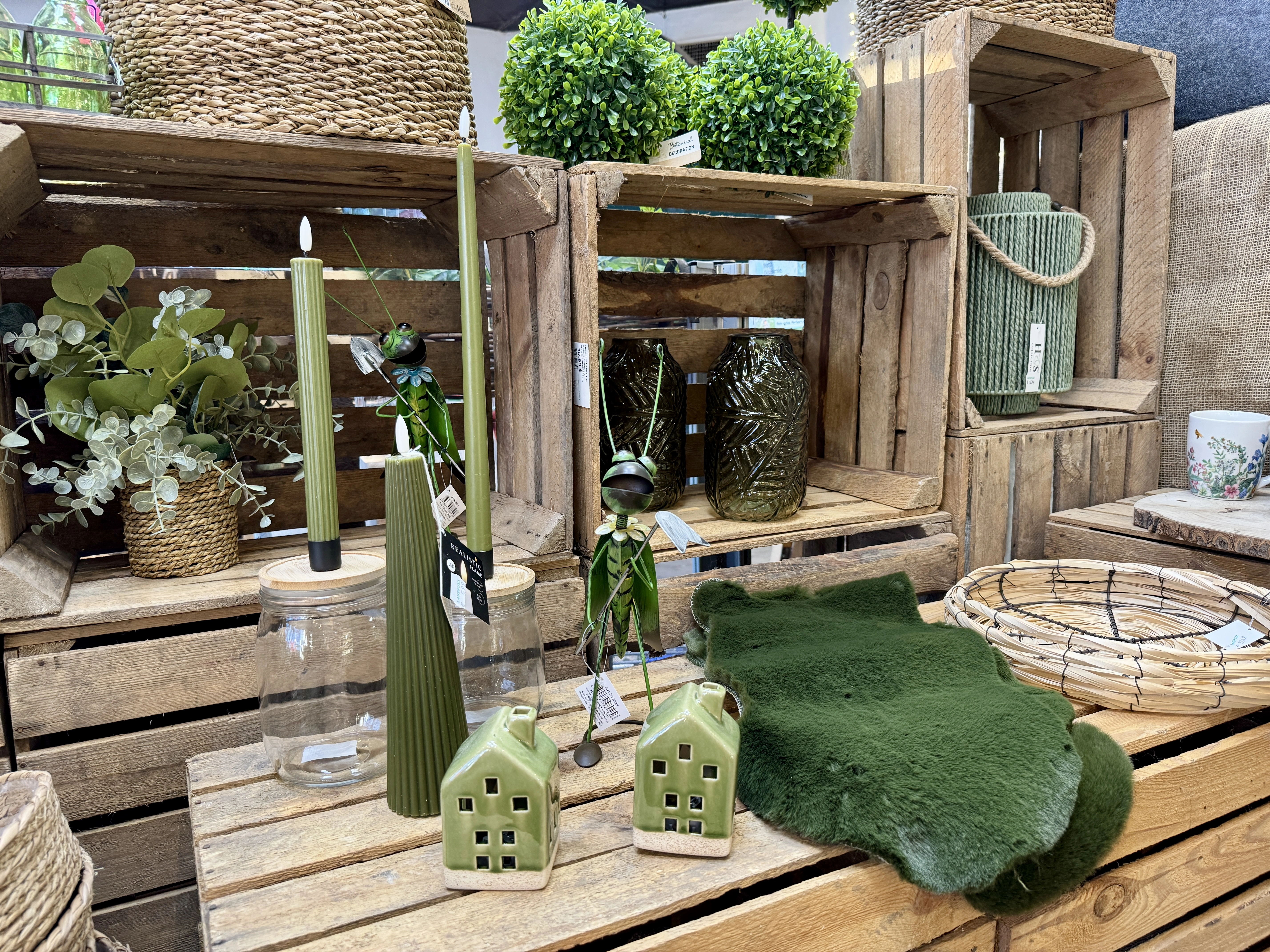 Unsere Dekoabteilung im Landfuxx Much mit saisonaler Deko, wie Kerzen und Kunstfelle in Grüntönen.