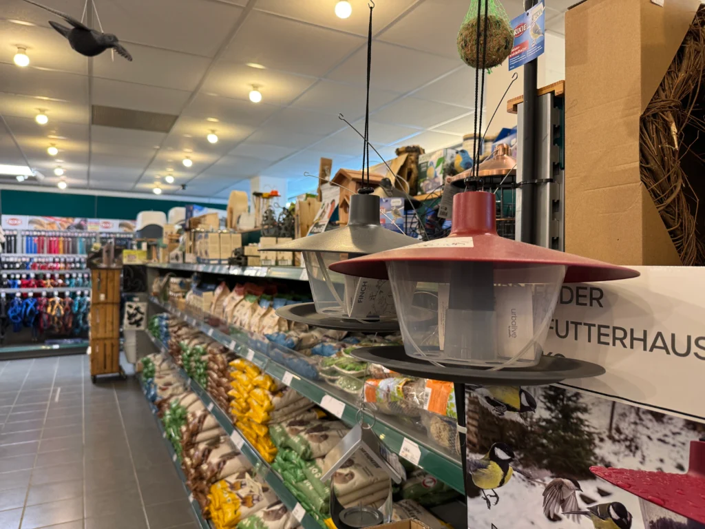 Gang mit großer Auswahl an Vogelfutter und Futterspendern im Landfuxx Much.