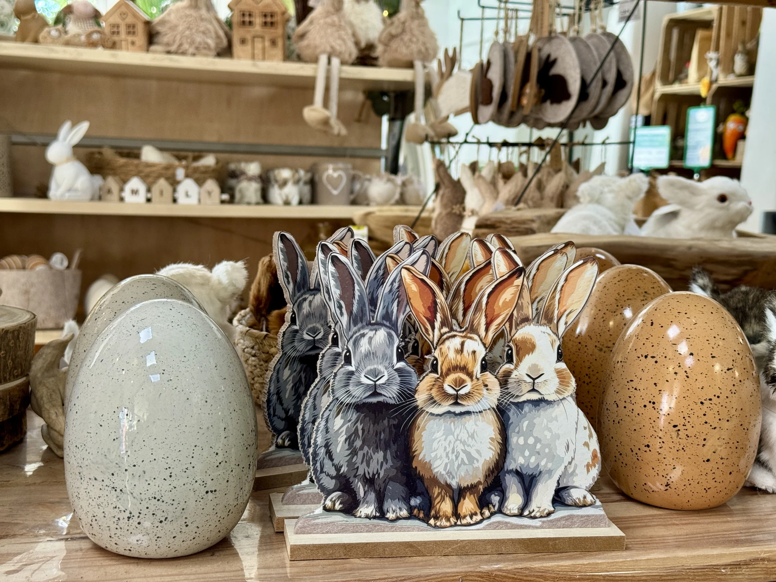 Osterdekoration mit Holzaufsteller mit drei Hasen und Ostereier in grau und braun im Landfuxx Much.